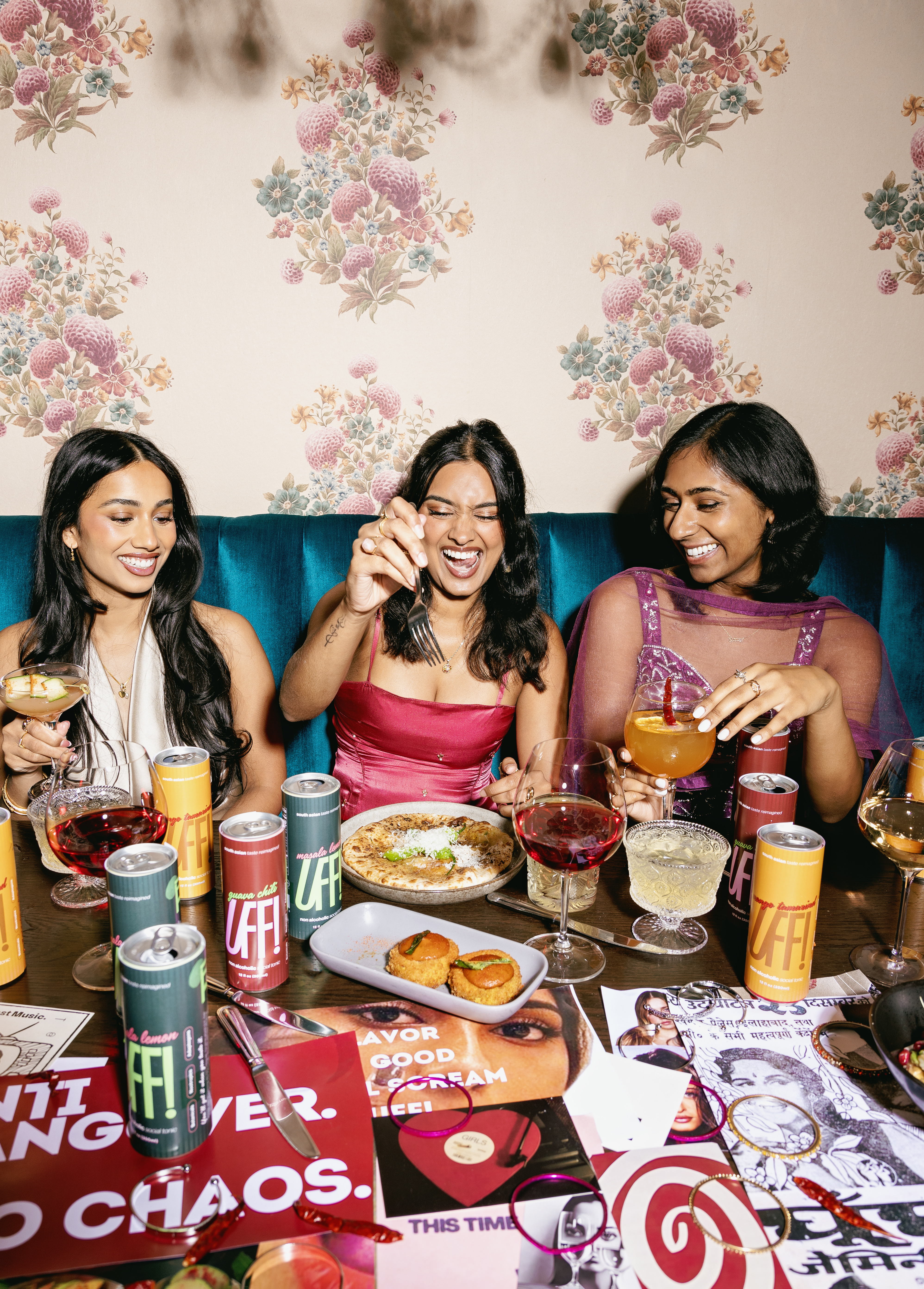 Three friends laughing over the table, cans and cocktails everywhere