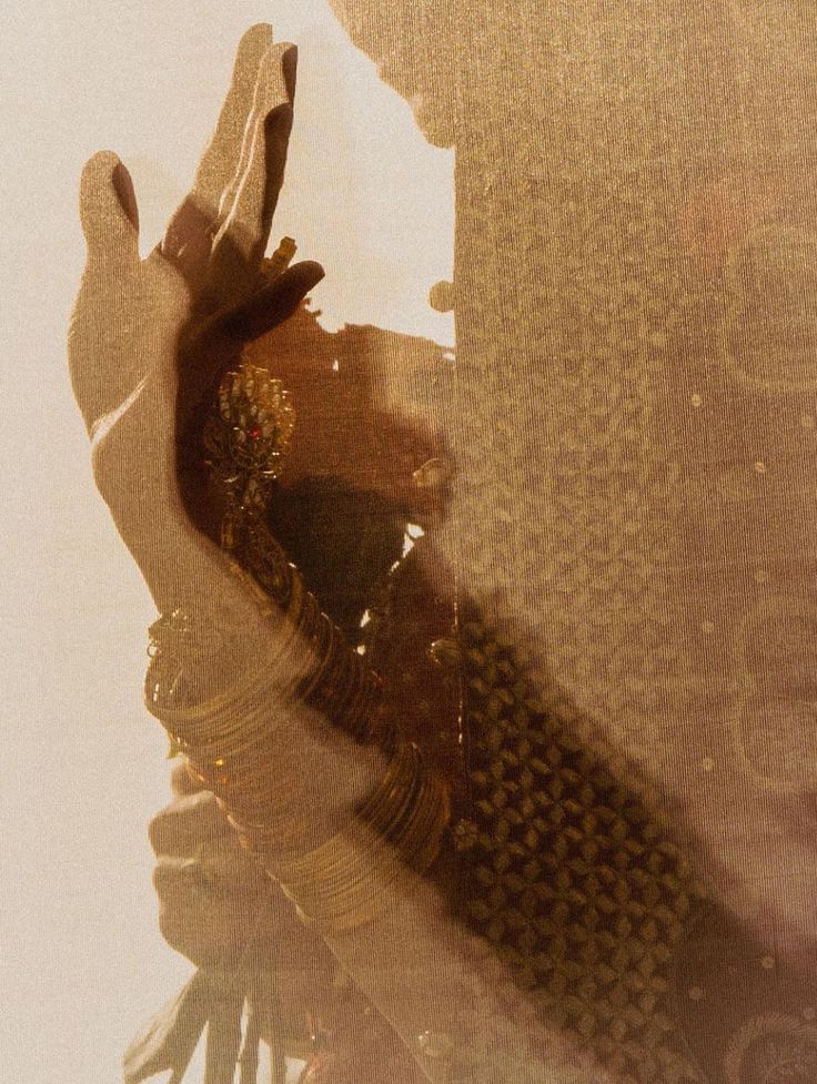 A hand raised in warm gold light, silk and bangles